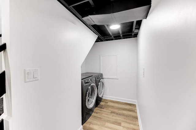 laundry area with laundry area, light wood finished floors, independent washer and dryer, and baseboards