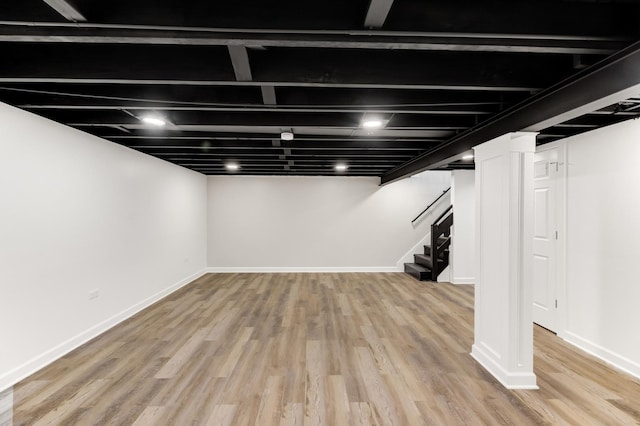 finished basement featuring light wood-type flooring, baseboards, and stairs