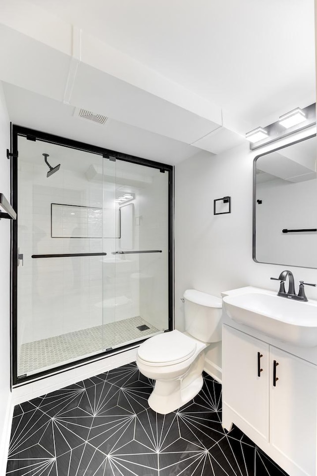 full bath featuring toilet, visible vents, vanity, a shower stall, and tile patterned floors