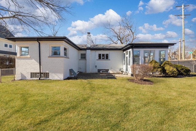 rear view of property featuring a yard, brick siding, fence, and a chimney