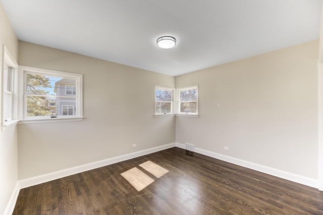 unfurnished room featuring visible vents, baseboards, and dark wood-style flooring