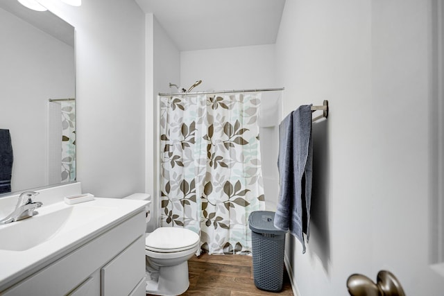 bathroom with toilet, curtained shower, wood finished floors, and vanity