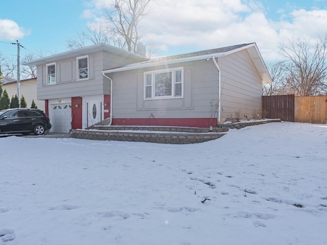 tri-level home featuring a garage and fence