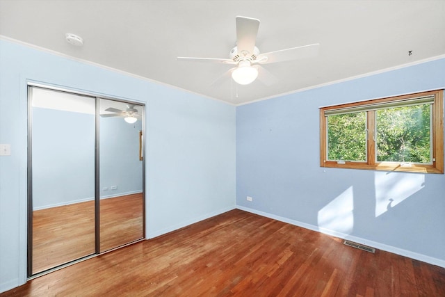 unfurnished bedroom with visible vents, crown molding, baseboards, and wood finished floors