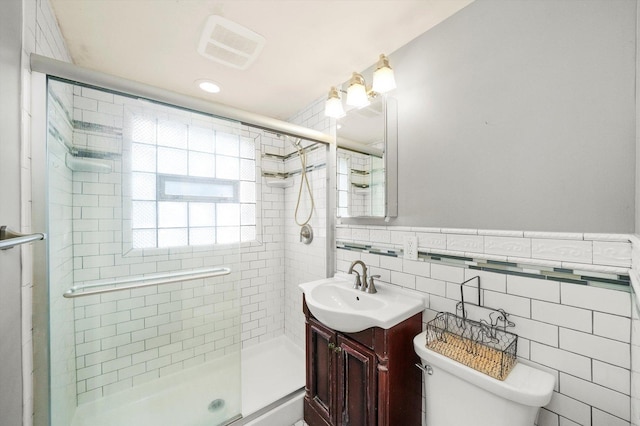 full bathroom featuring toilet, a stall shower, visible vents, and tile walls