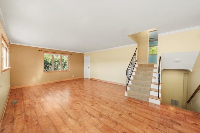 unfurnished living room with light wood finished floors, baseboards, visible vents, and ornamental molding