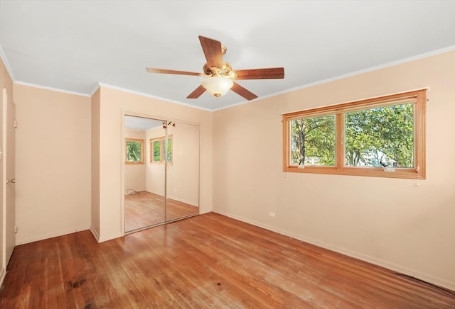 unfurnished bedroom with ornamental molding, a closet, wood finished floors, and a ceiling fan