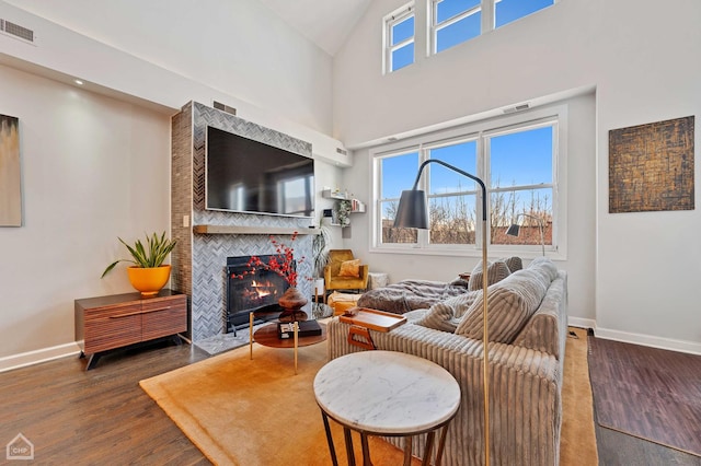 living room with baseboards, a fireplace, visible vents, and wood finished floors