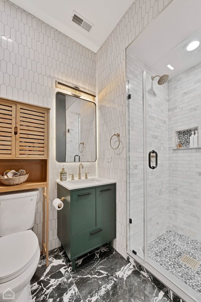 bathroom with a stall shower, visible vents, toilet, marble finish floor, and tile walls