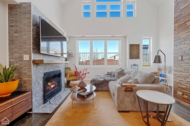 living area with a towering ceiling, a fireplace with flush hearth, baseboards, and wood finished floors