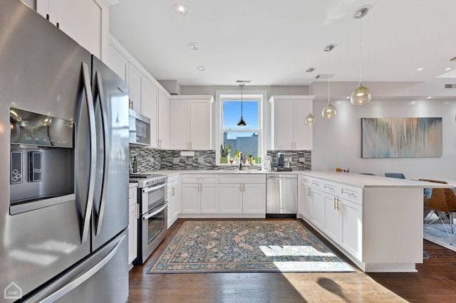 kitchen featuring a peninsula, white cabinetry, appliances with stainless steel finishes, and dark wood-type flooring