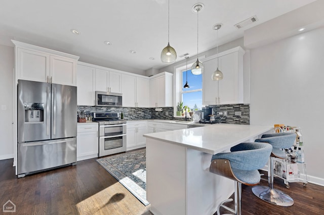 kitchen featuring a peninsula, appliances with stainless steel finishes, a sink, and white cabinetry