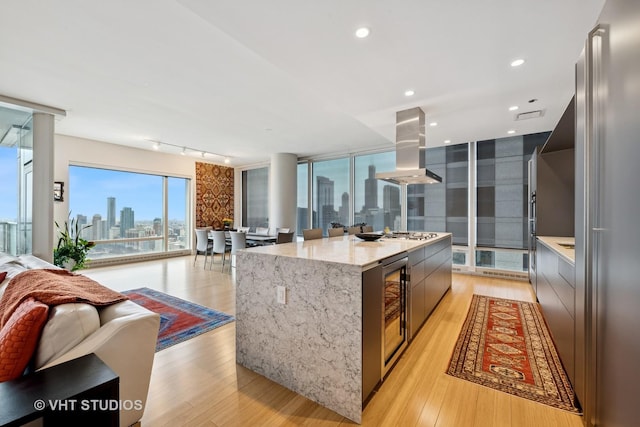 kitchen featuring light wood-style floors, a view of city, open floor plan, and island exhaust hood