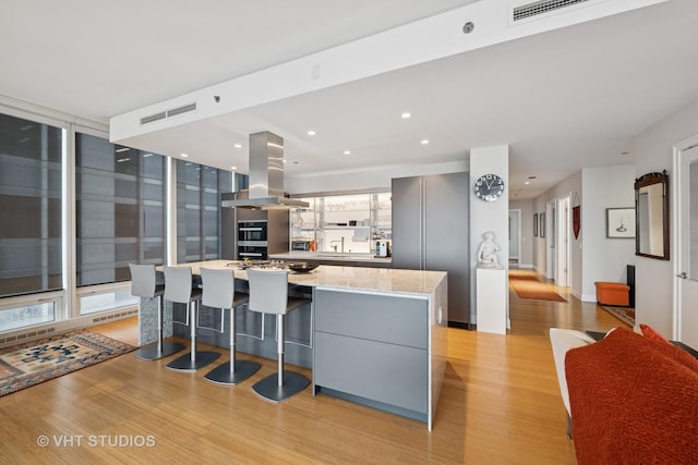 kitchen featuring visible vents, light wood-style floors, gray cabinets, modern cabinets, and island exhaust hood