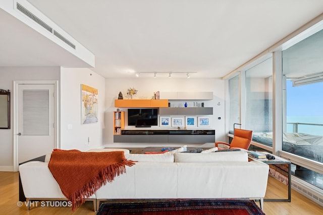 living room with floor to ceiling windows, visible vents, track lighting, and wood finished floors