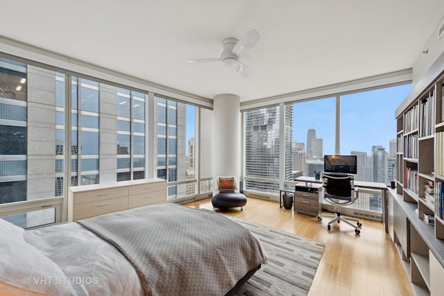 bedroom with ceiling fan, a wall of windows, and wood finished floors