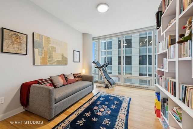 sitting room with a wall of windows, baseboards, and wood finished floors