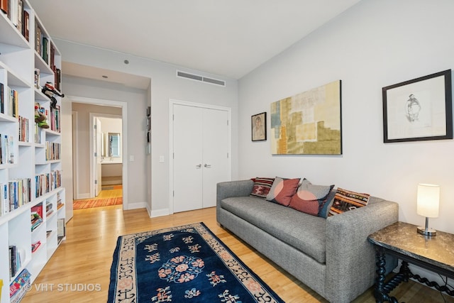 living area with light wood-type flooring, visible vents, and baseboards