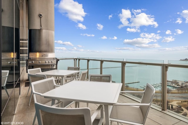 balcony featuring grilling area, outdoor dining area, and a water view