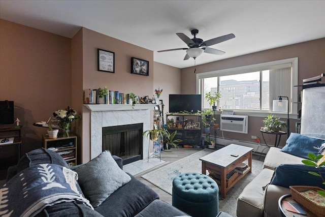 living room featuring an AC wall unit, a tiled fireplace, and a ceiling fan