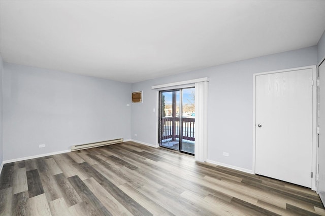 spare room with a baseboard radiator, wood finished floors, and baseboards