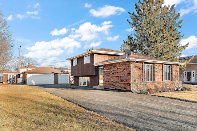 tri-level home featuring a garage, an outbuilding, brick siding, and a front yard