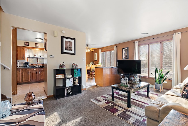 living room with light tile patterned flooring, ceiling fan, visible vents, and light colored carpet