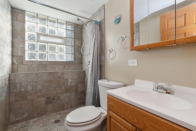 full bath featuring tiled shower, vanity, and toilet