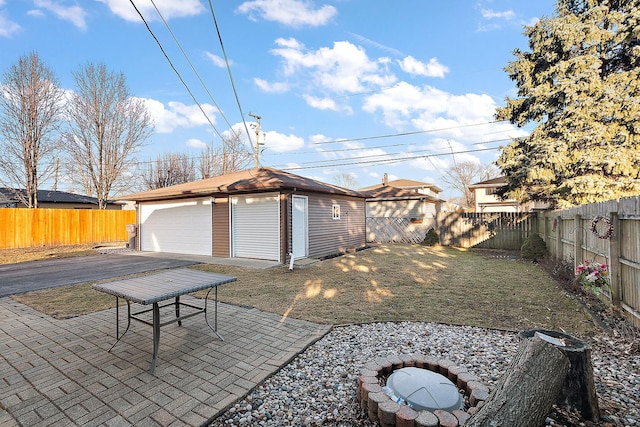 view of yard with a fenced backyard, a detached garage, a patio, and an outbuilding