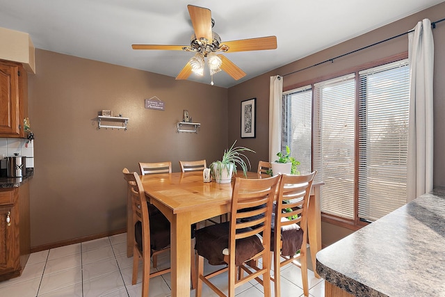 dining area with light tile patterned floors, a ceiling fan, and baseboards