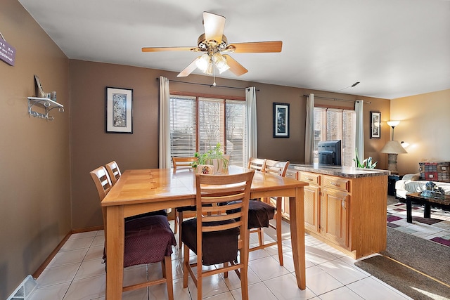 dining room with light tile patterned floors, visible vents, baseboards, and a ceiling fan