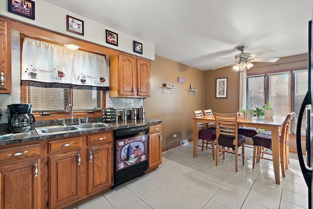 kitchen featuring dark countertops, backsplash, brown cabinetry, a sink, and dishwasher