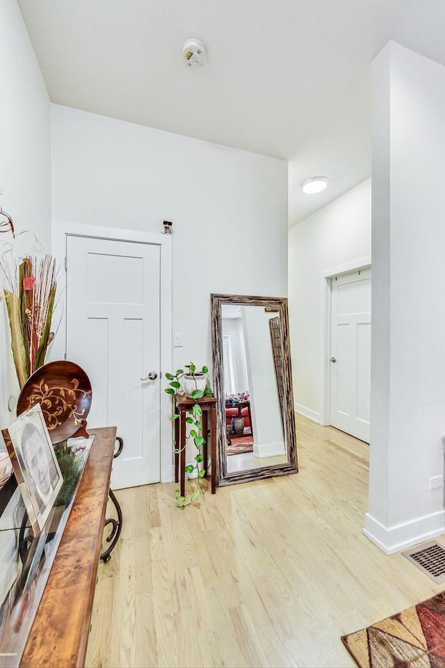 hall featuring visible vents, baseboards, and wood finished floors