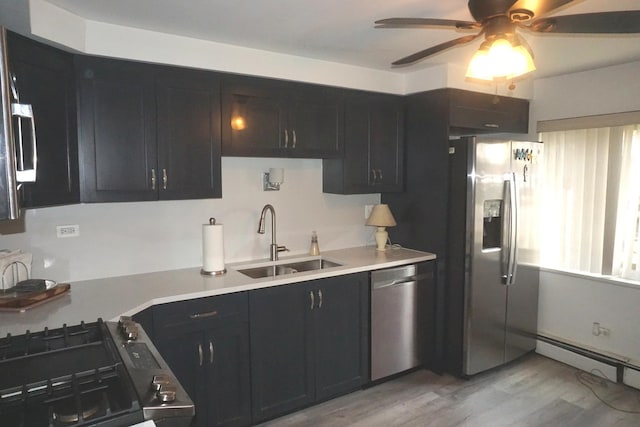 kitchen featuring a baseboard radiator, appliances with stainless steel finishes, light countertops, light wood-style floors, and a sink