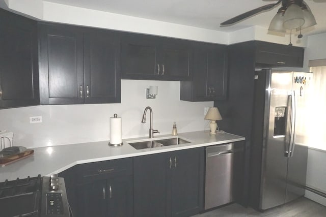 kitchen with a baseboard radiator, light countertops, appliances with stainless steel finishes, a ceiling fan, and a sink