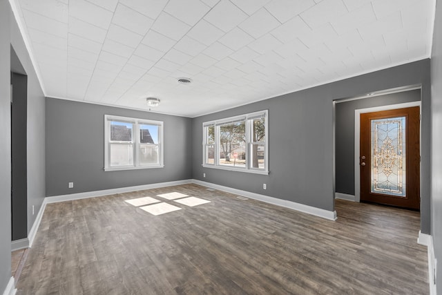 empty room with wood finished floors, visible vents, and baseboards