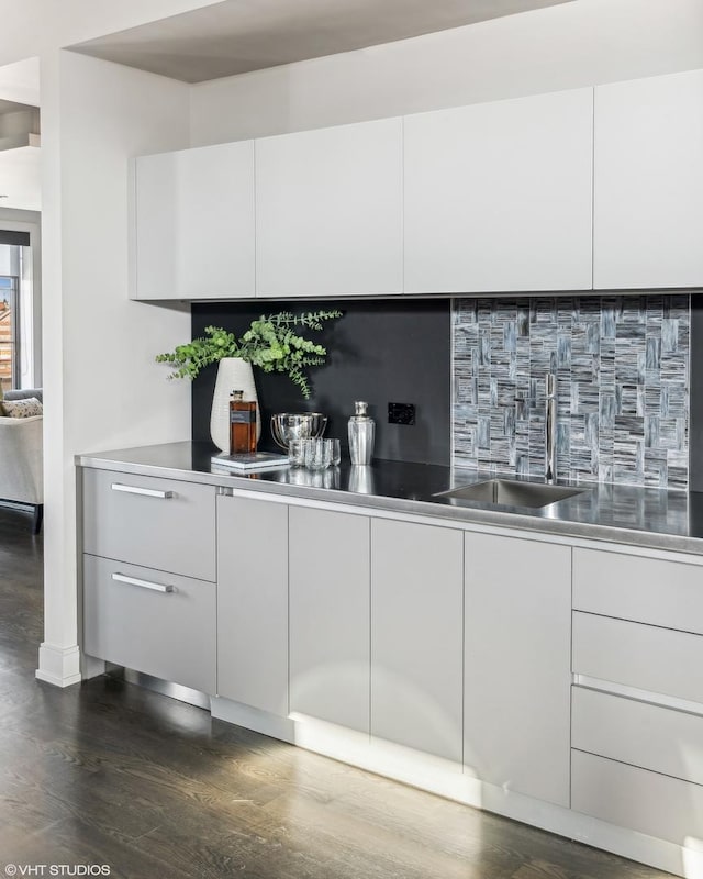 bar featuring tasteful backsplash, dark wood-style flooring, and a sink