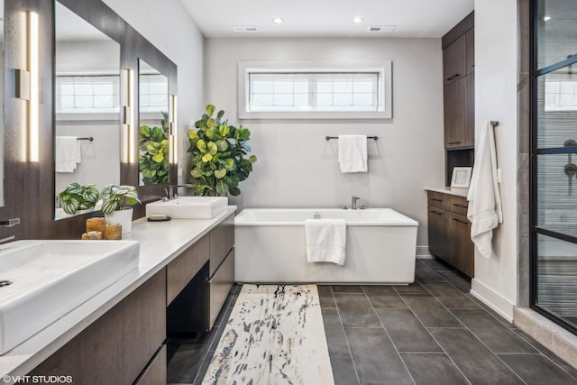 bathroom featuring a freestanding tub, visible vents, a sink, and double vanity