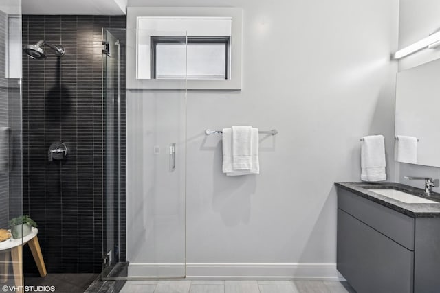 full bathroom featuring a shower stall, baseboards, and vanity