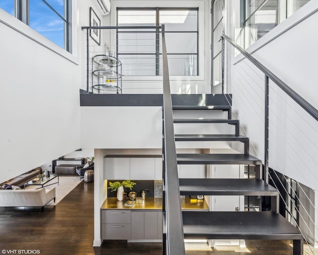 stairs with a high ceiling and wood finished floors