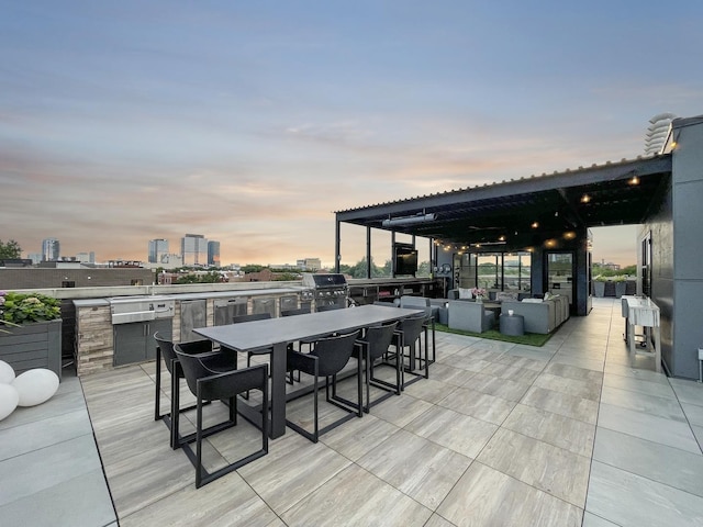 patio terrace at dusk with a view of city, outdoor lounge area, area for grilling, and outdoor dining space