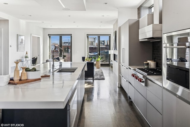 kitchen featuring a spacious island, modern cabinets, light countertops, stainless steel gas stovetop, and a sink