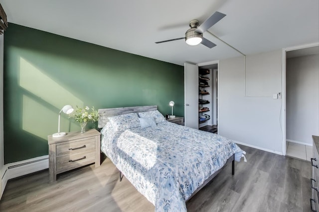 bedroom with ceiling fan, baseboards, baseboard heating, and wood finished floors