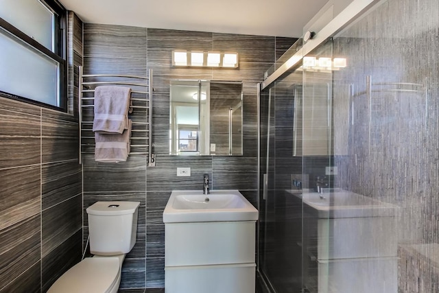 full bathroom featuring a stall shower, vanity, toilet, and tile walls