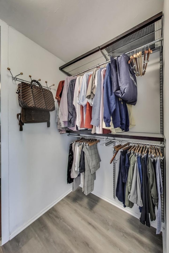 spacious closet with a notable chandelier and wood finished floors