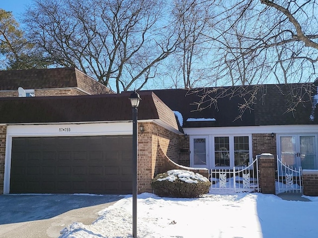 view of front of house featuring aphalt driveway, brick siding, and a garage