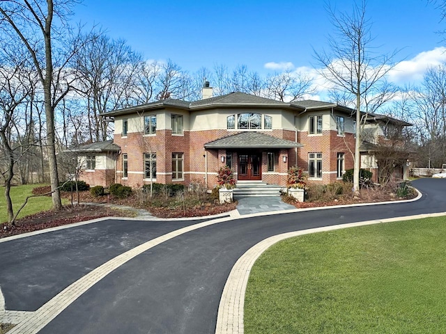 exterior space with brick siding, a chimney, and a front yard