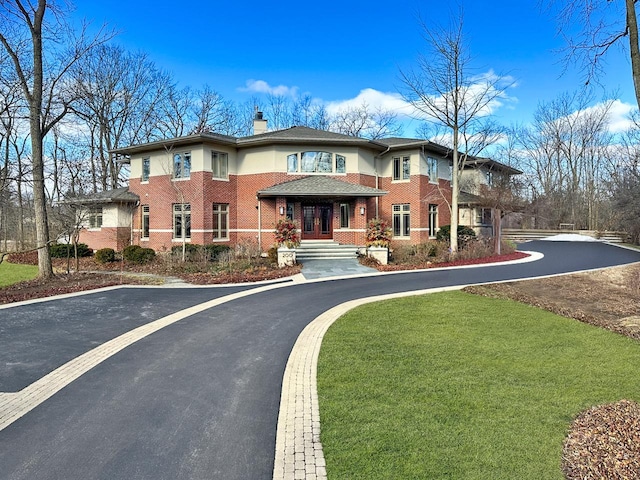 view of front of property with a front yard, french doors, brick siding, and a chimney