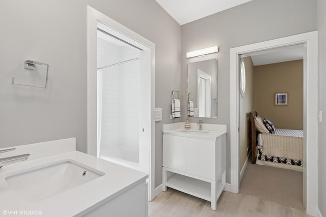 bathroom with baseboards, two vanities, a sink, and shower / bathtub combination