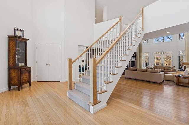 stairs featuring a towering ceiling, baseboards, and wood finished floors